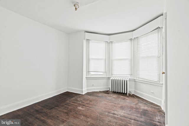 spare room featuring dark hardwood / wood-style flooring and radiator