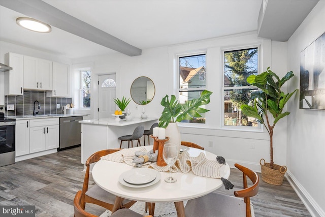 kitchen featuring hardwood / wood-style floors, decorative backsplash, white cabinetry, and appliances with stainless steel finishes