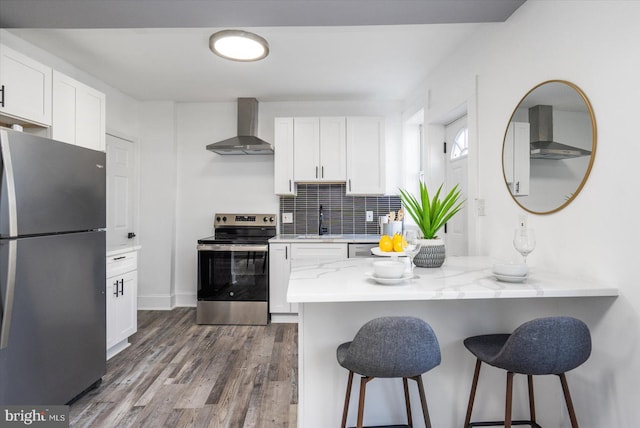 kitchen featuring dark hardwood / wood-style floors, white cabinetry, wall chimney range hood, and stainless steel appliances