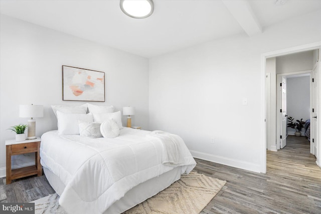 bedroom featuring beam ceiling and dark hardwood / wood-style flooring