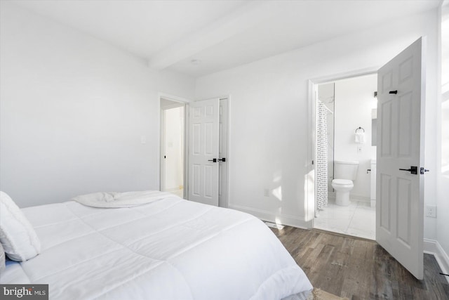 bedroom featuring beam ceiling, dark wood-type flooring, and ensuite bath