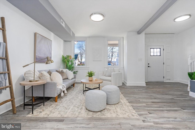 living room featuring beamed ceiling and hardwood / wood-style flooring