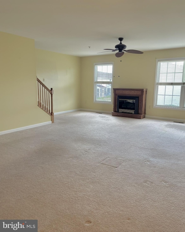 unfurnished living room with light carpet, plenty of natural light, and ceiling fan