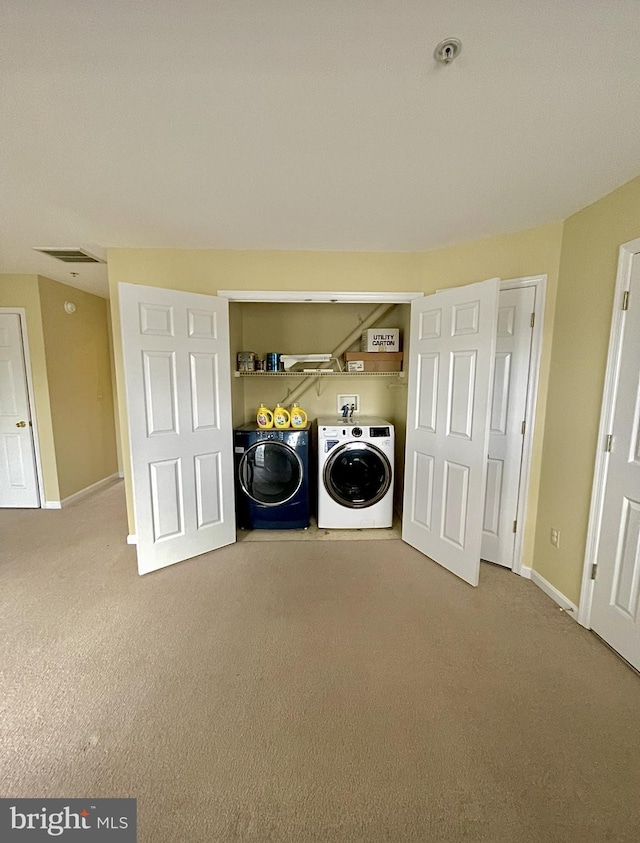 laundry room featuring washing machine and clothes dryer and light carpet