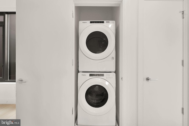 laundry room featuring light wood-type flooring and stacked washing maching and dryer