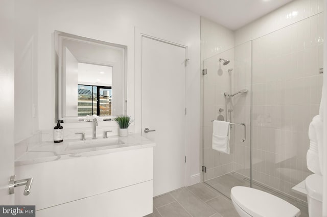 bathroom with tile patterned flooring, vanity, toilet, and walk in shower