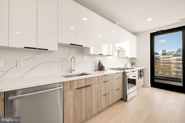 kitchen with sink, appliances with stainless steel finishes, decorative backsplash, white cabinets, and light wood-type flooring