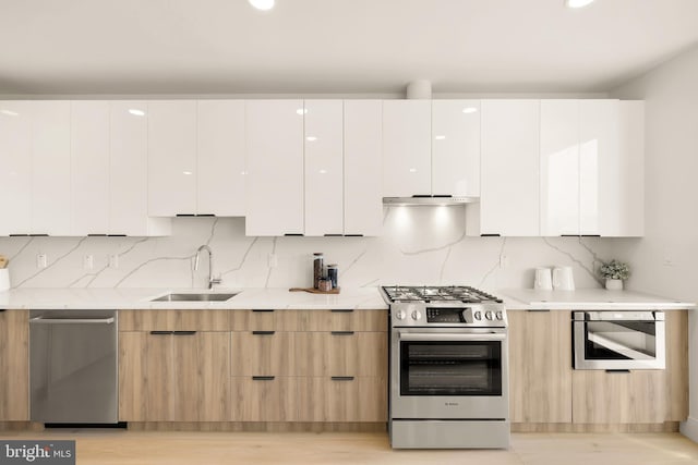 kitchen featuring sink, range hood, tasteful backsplash, white cabinetry, and stainless steel appliances