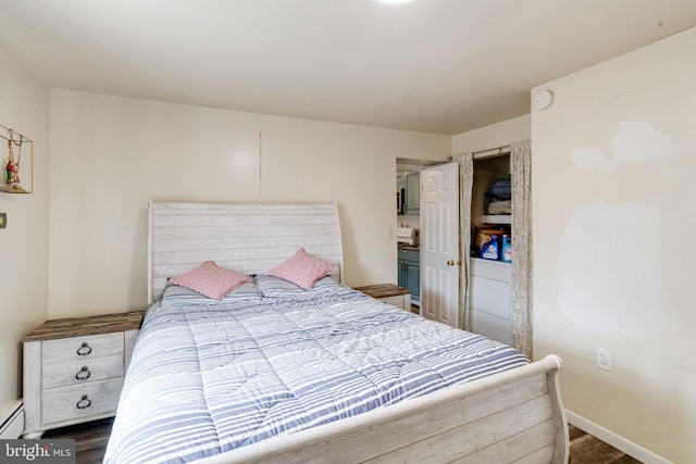 bedroom with dark hardwood / wood-style floors and a baseboard radiator