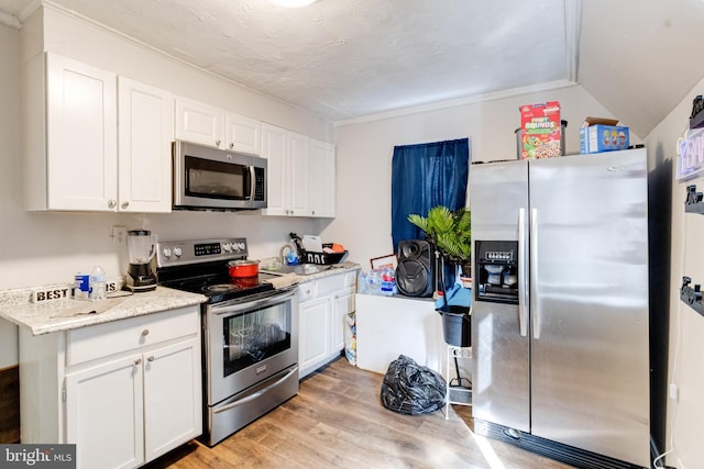 kitchen with light hardwood / wood-style floors, appliances with stainless steel finishes, white cabinetry, and light stone counters