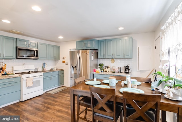 kitchen with sink, appliances with stainless steel finishes, tasteful backsplash, and dark hardwood / wood-style floors