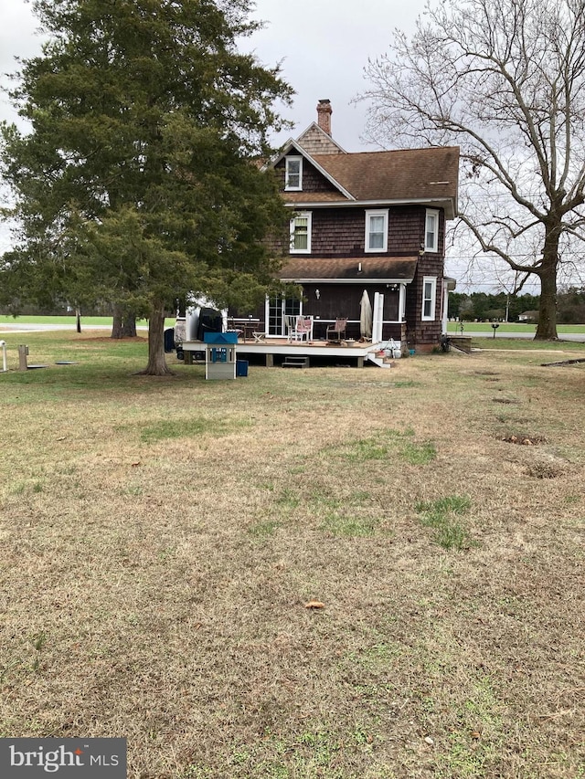 rear view of property featuring a deck and a yard