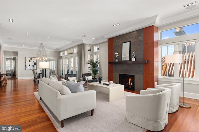 living room with a tiled fireplace, ornamental molding, plenty of natural light, and hardwood / wood-style floors