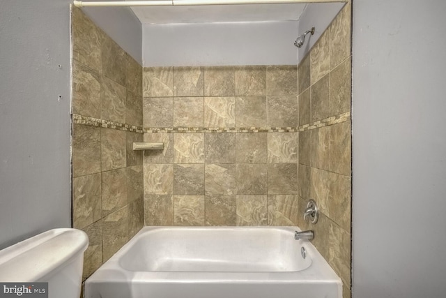 bathroom with tiled shower / bath combo and toilet