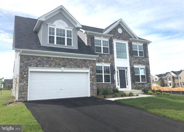 view of front of home featuring aphalt driveway, stone siding, a garage, and a front lawn