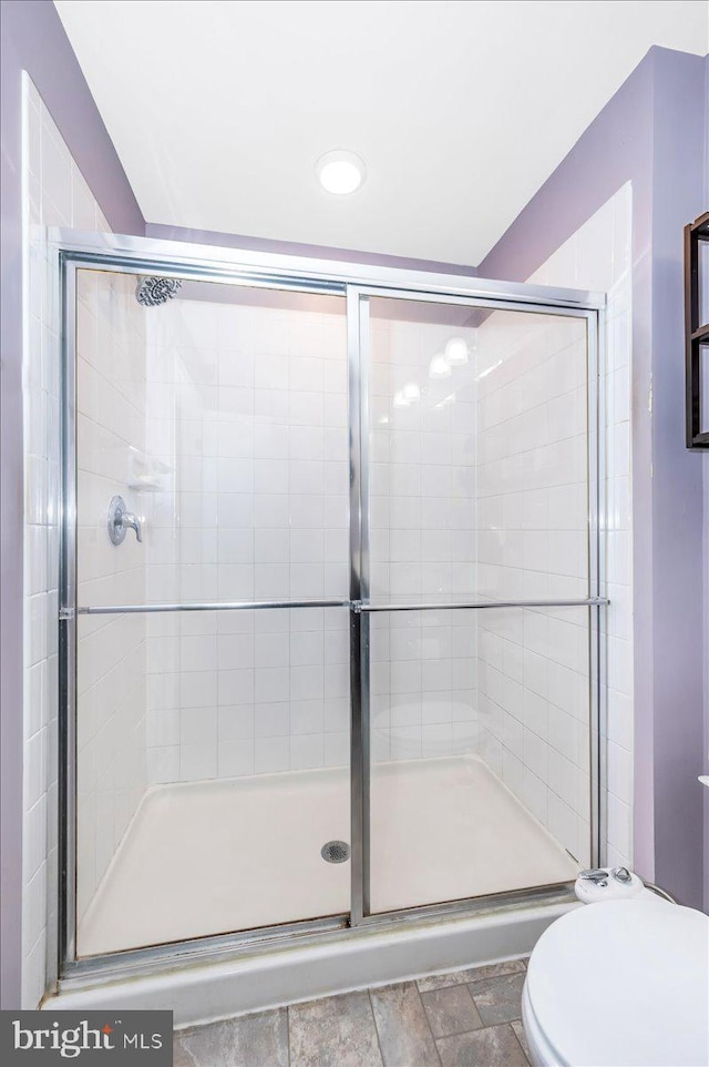 bathroom with toilet and an enclosed shower