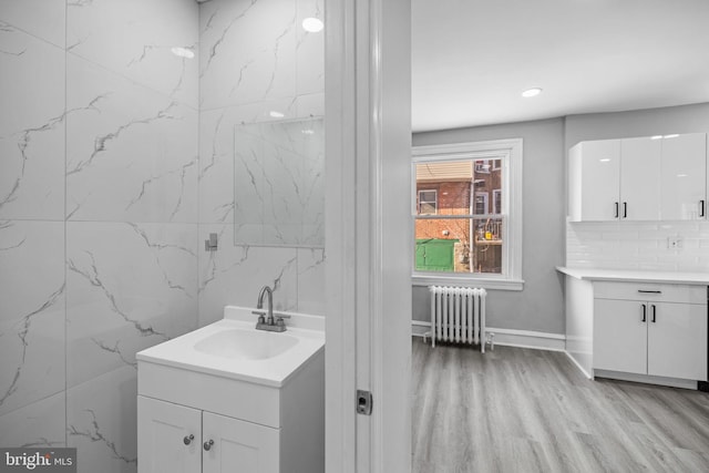 bathroom with hardwood / wood-style floors, tasteful backsplash, vanity, and radiator heating unit