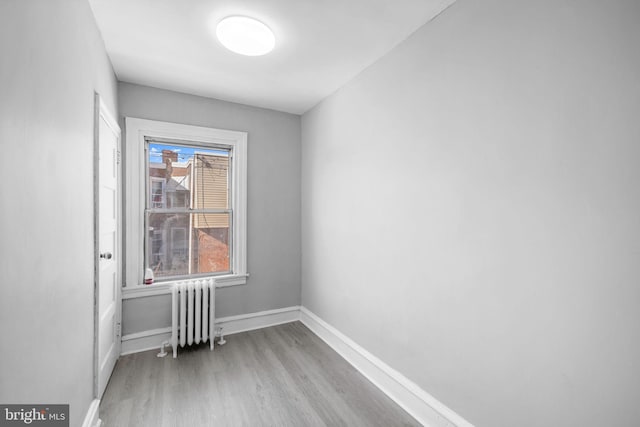 spare room featuring radiator heating unit and light hardwood / wood-style flooring