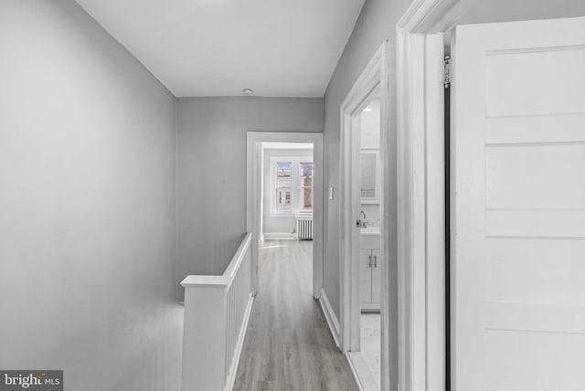 hall with light hardwood / wood-style floors and radiator heating unit