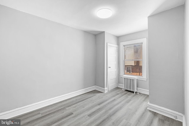 empty room featuring radiator and light hardwood / wood-style flooring