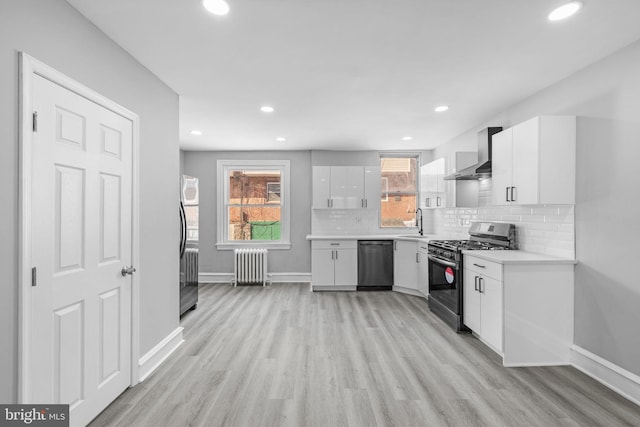 kitchen with wall chimney range hood, dishwashing machine, white cabinets, stainless steel gas stove, and radiator heating unit