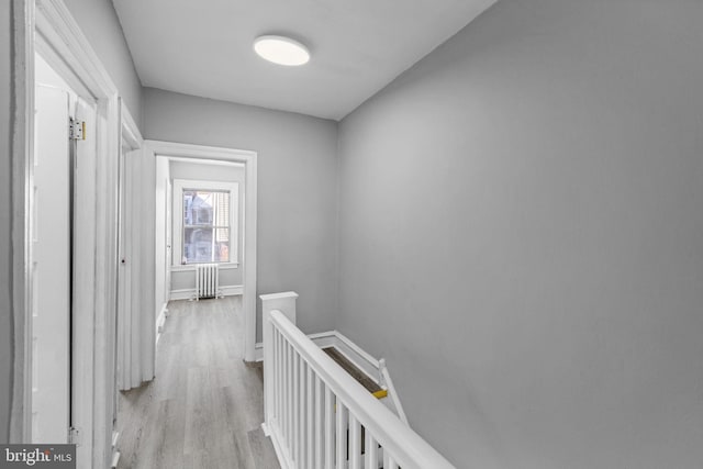 corridor featuring radiator heating unit and light hardwood / wood-style floors