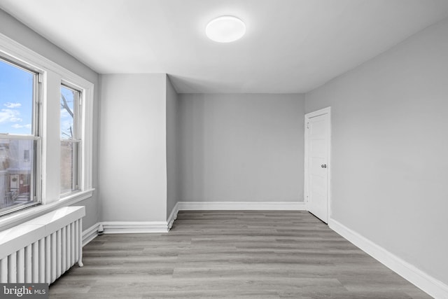 empty room with radiator heating unit and light wood-type flooring