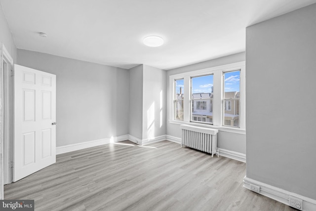 empty room with radiator heating unit and light hardwood / wood-style flooring