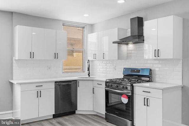 kitchen featuring white cabinets, wall chimney exhaust hood, black dishwasher, sink, and stainless steel range with gas stovetop