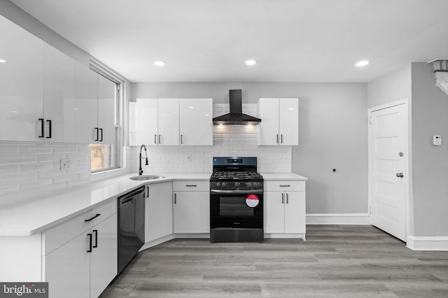 kitchen with wall chimney exhaust hood, gas stove, white cabinetry, black dishwasher, and sink