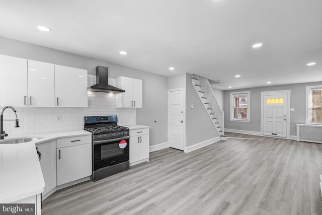 kitchen featuring white cabinetry, wall chimney exhaust hood, gas stove, and sink