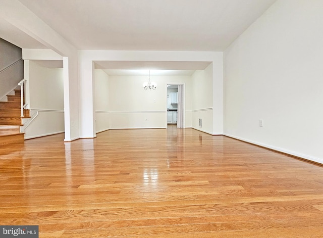 spare room featuring light hardwood / wood-style flooring and a notable chandelier