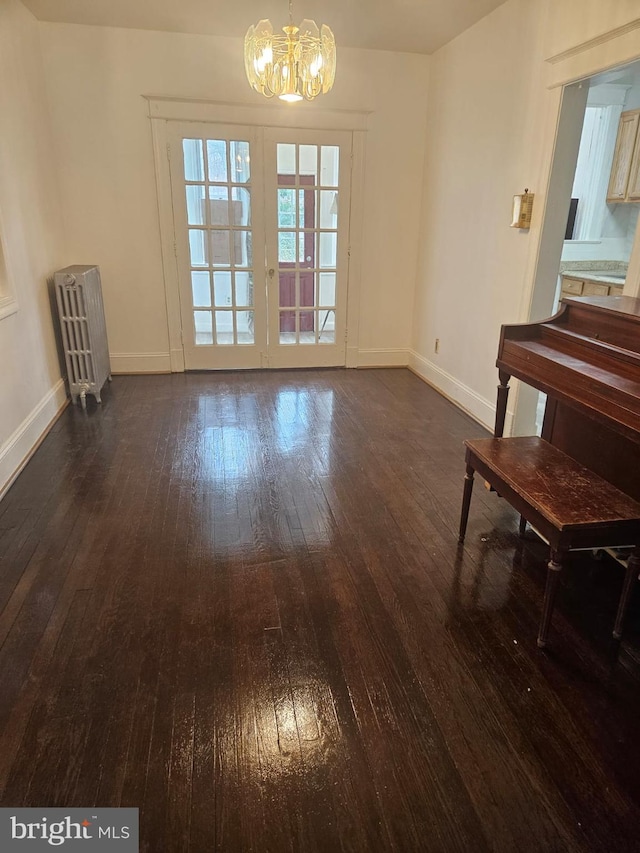 unfurnished dining area featuring dark hardwood / wood-style flooring, radiator, and a notable chandelier