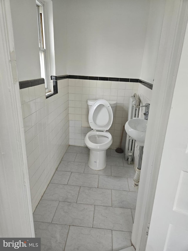 bathroom featuring tile patterned floors, sink, tile walls, and toilet