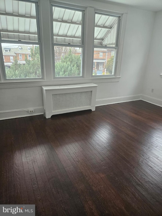 unfurnished room with radiator heating unit and dark wood-type flooring