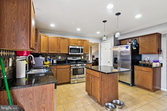 kitchen with a center island, sink, hanging light fixtures, ornamental molding, and stainless steel appliances