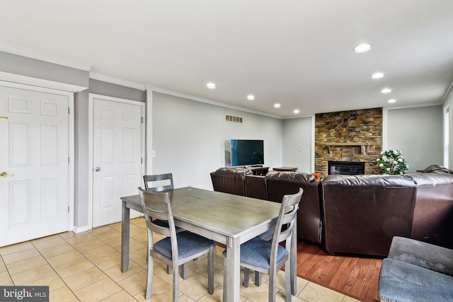 dining area featuring a fireplace, light tile patterned floors, and ornamental molding