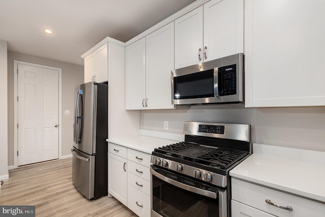 kitchen with stainless steel appliances, white cabinetry, and light hardwood / wood-style flooring