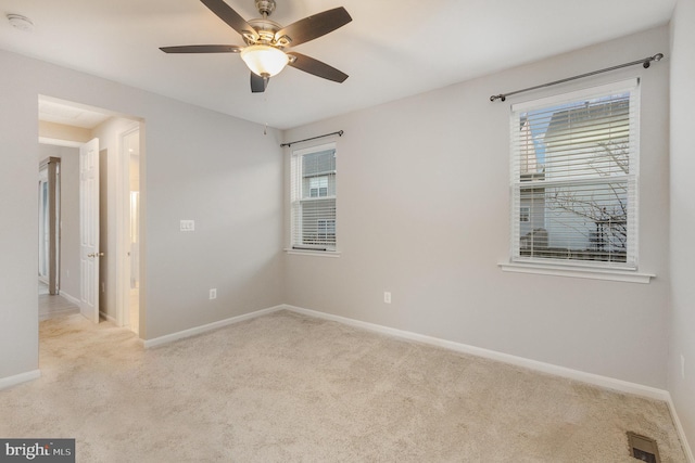 carpeted spare room with ceiling fan and plenty of natural light