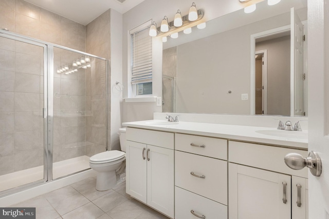 bathroom featuring toilet, vanity, tile patterned floors, and a shower with shower door