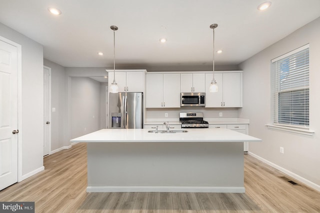 kitchen featuring a center island with sink, hanging light fixtures, and appliances with stainless steel finishes