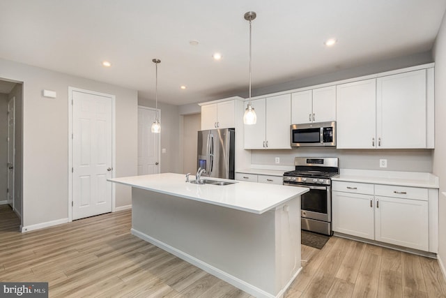 kitchen featuring white cabinets, hanging light fixtures, light hardwood / wood-style flooring, an island with sink, and appliances with stainless steel finishes