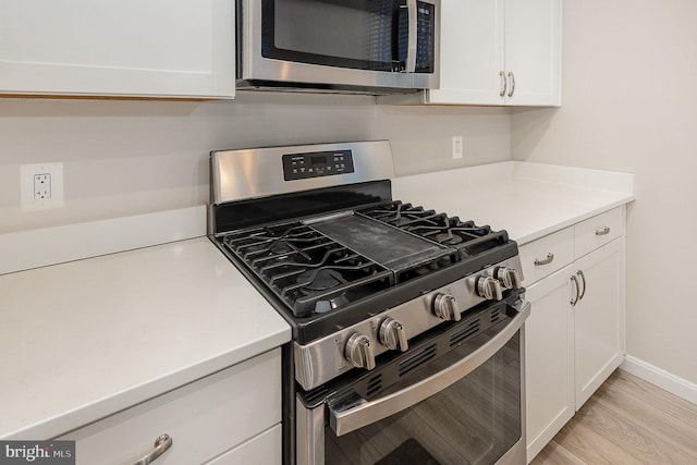 kitchen featuring appliances with stainless steel finishes, light hardwood / wood-style floors, and white cabinetry