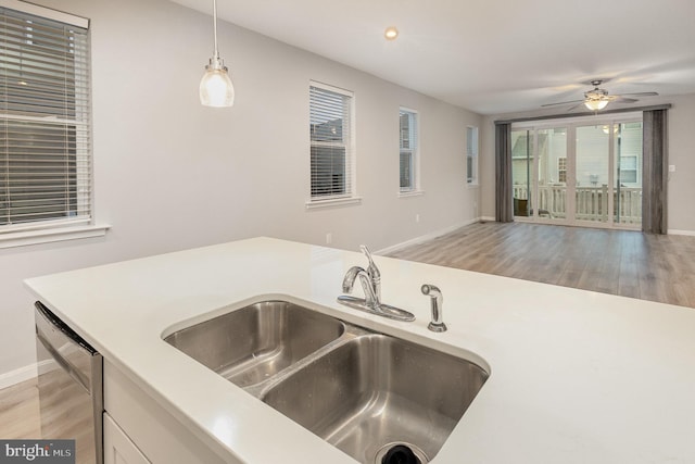 kitchen featuring ceiling fan, sink, stainless steel dishwasher, decorative light fixtures, and light wood-type flooring