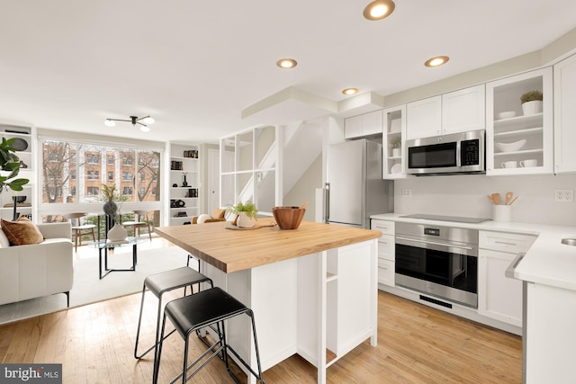 kitchen featuring butcher block countertops, white cabinetry, a kitchen bar, and stainless steel appliances