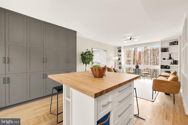 kitchen with a center island, white cabinetry, butcher block counters, and a breakfast bar area