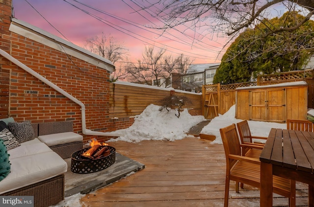 deck at dusk featuring an outdoor living space with a fire pit