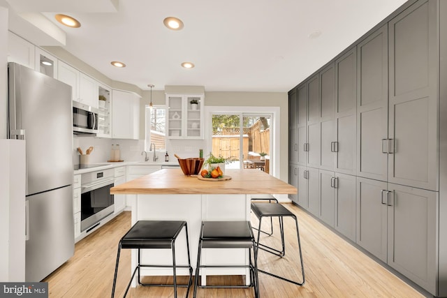 kitchen featuring a center island, wooden counters, white cabinets, gray cabinets, and appliances with stainless steel finishes