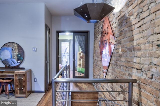 hall with brick wall, baseboards, and wood finished floors