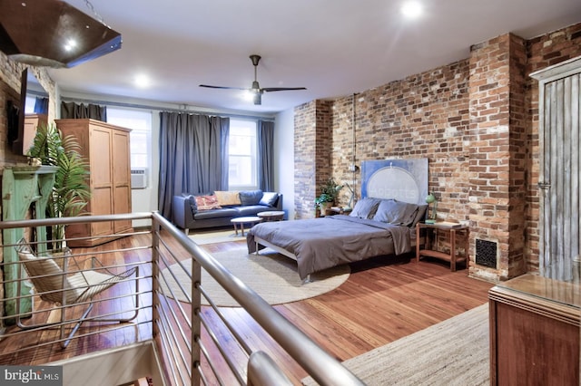 bedroom featuring brick wall and wood finished floors